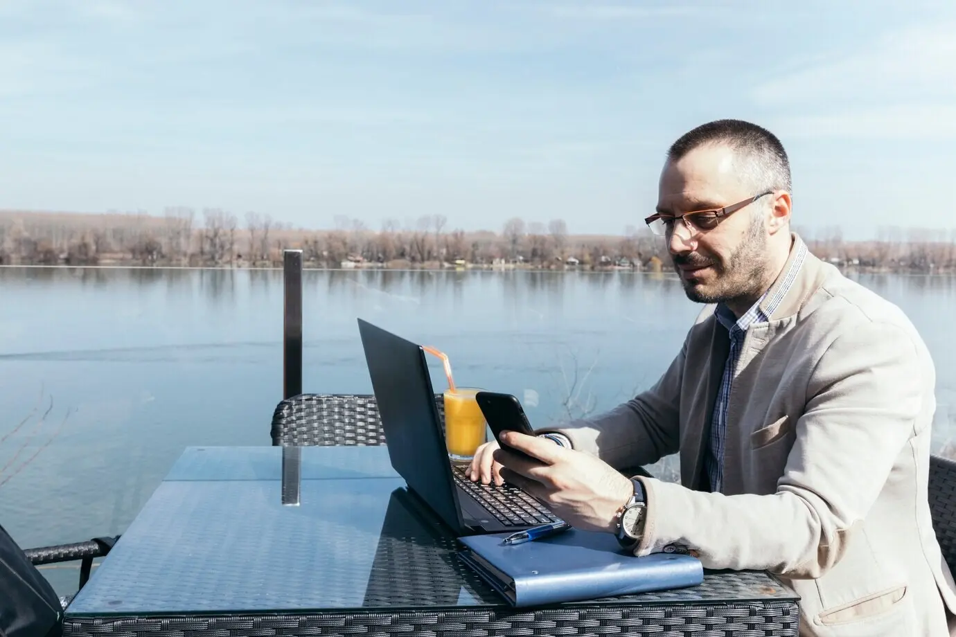 Geschäftsmann nutzt Smartphone und Laptop in Wassernähe